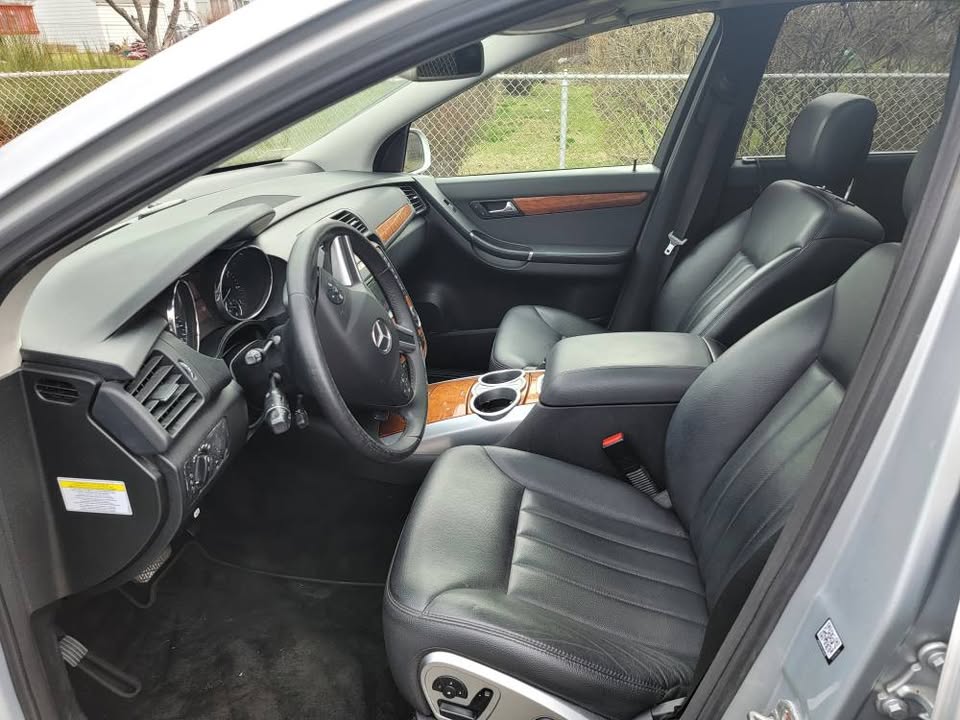 Front interior view of 2009 Mercedes-Benz R350 showing black leather seats, wood trim, center console, and steering wheel