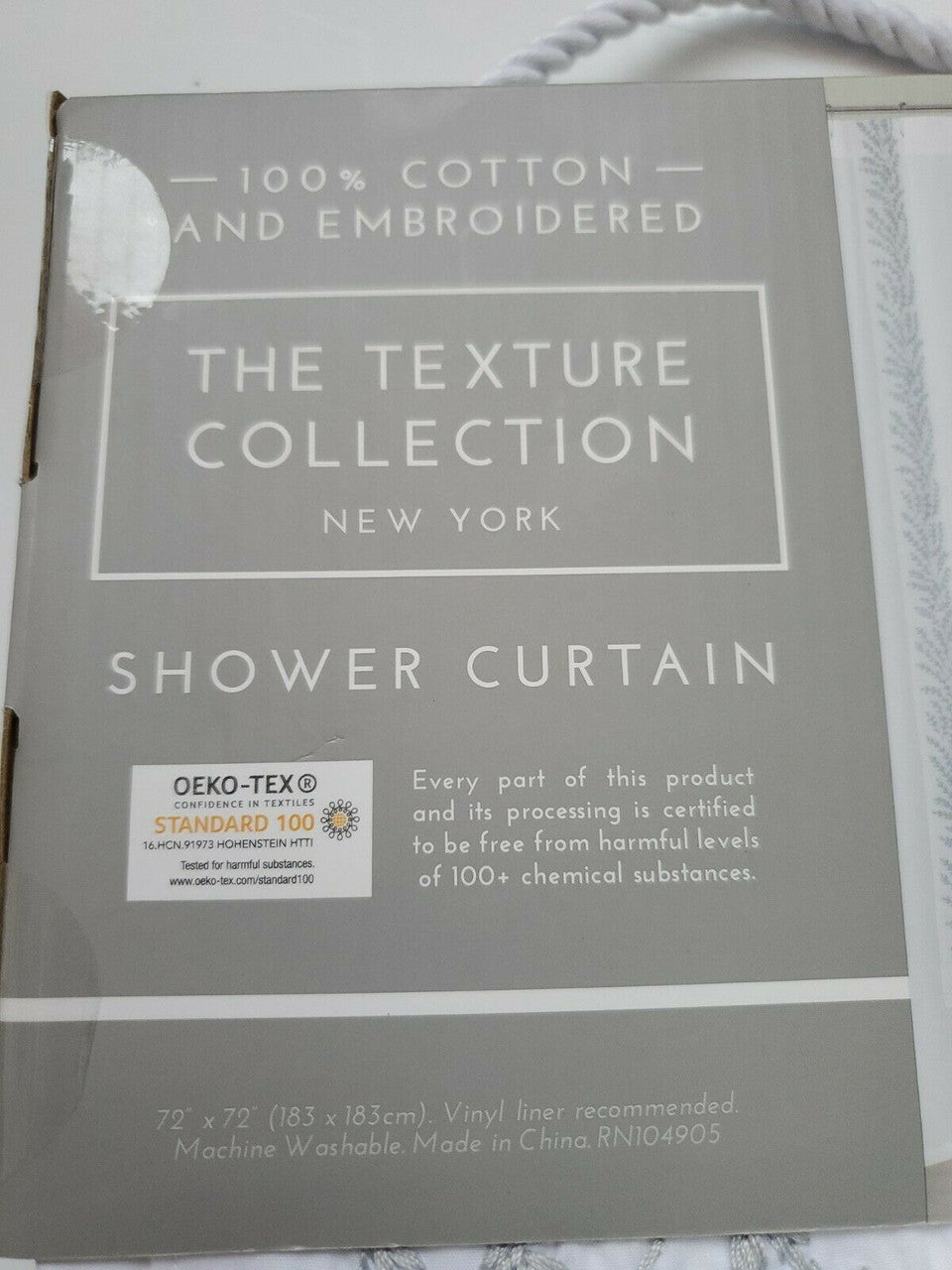 Folded white 100% cotton embroidered shower curtain from The Texture Collection shown in retail packaging