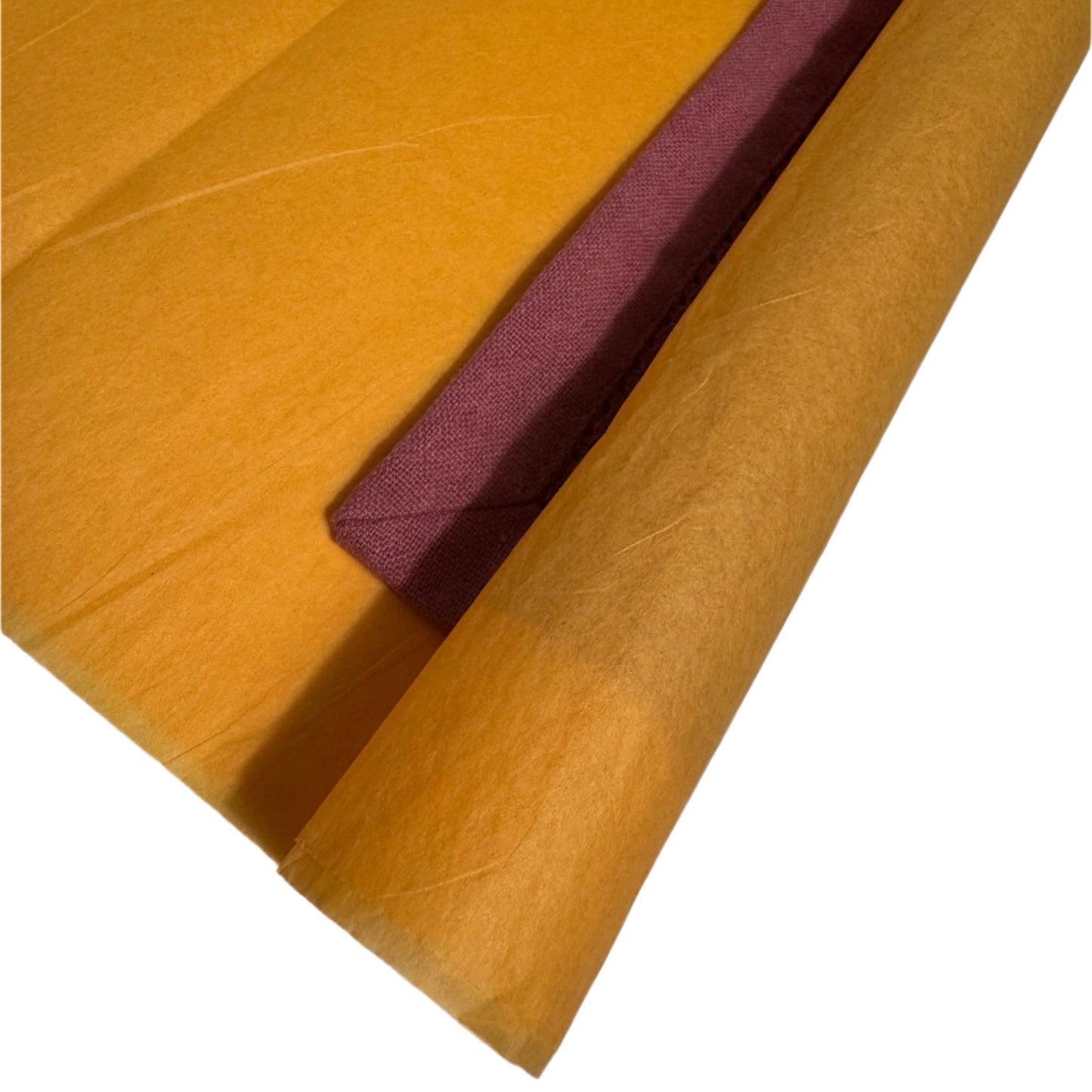 A close-up of two folded cloth napkins, one in a rich mustard yellow and the other in a deep burgundy, overlapping to showcase their fine fabric texture and contrasting colors. The edges are neatly folded, emphasizing the premium quality of the cotton napkins