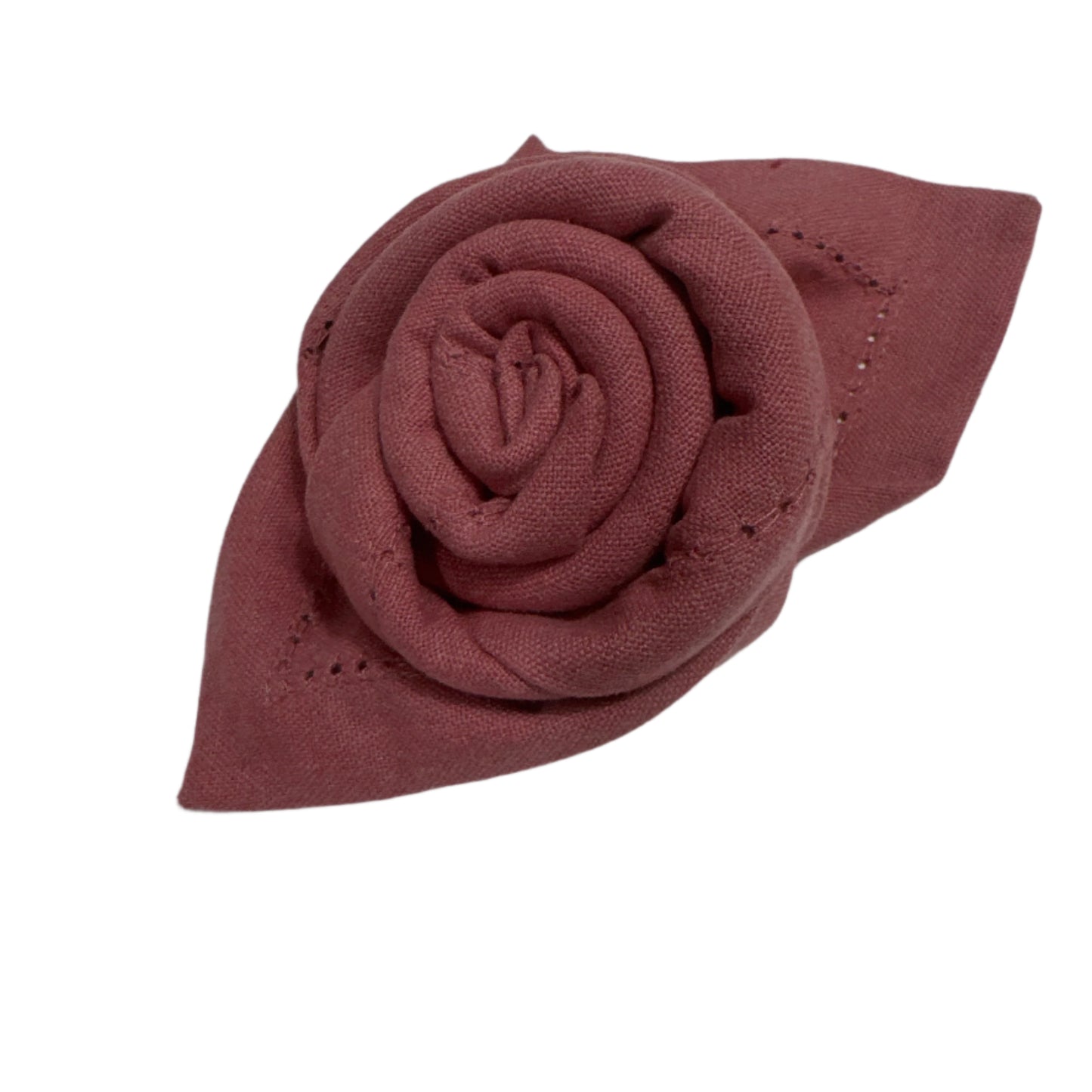 Close-up shot of a blush pink cotton napkin artfully folded into a rose shape, with intricate hemstitch detailing along the edges. The soft texture of the cotton is highlighted, emphasizing the napkin's elegant and stylish presentation