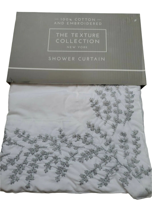 Folded white 100% cotton embroidered shower curtain from The Texture Collection shown in retail packaging