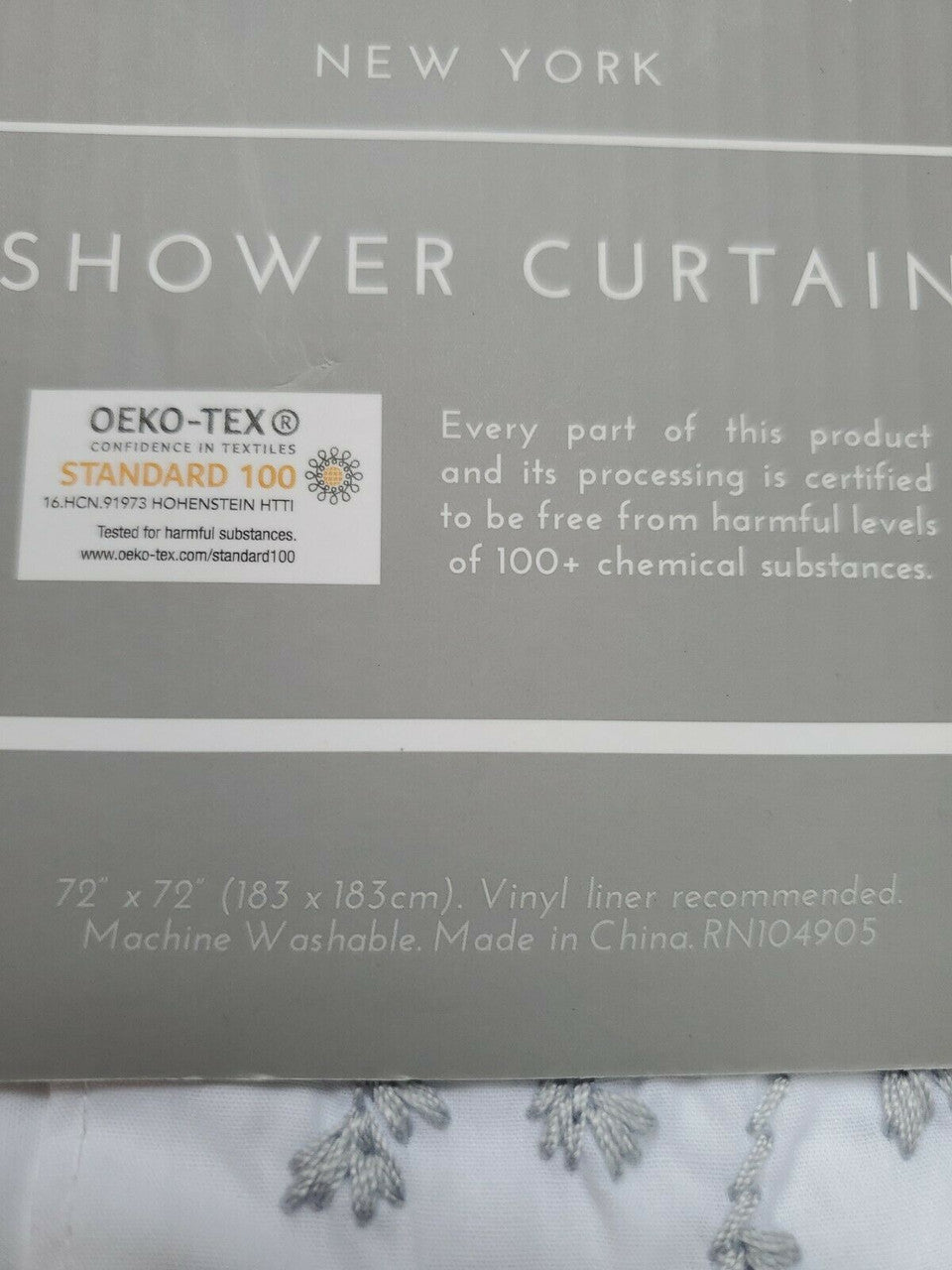 Folded white 100% cotton embroidered shower curtain from The Texture Collection shown in retail packaging