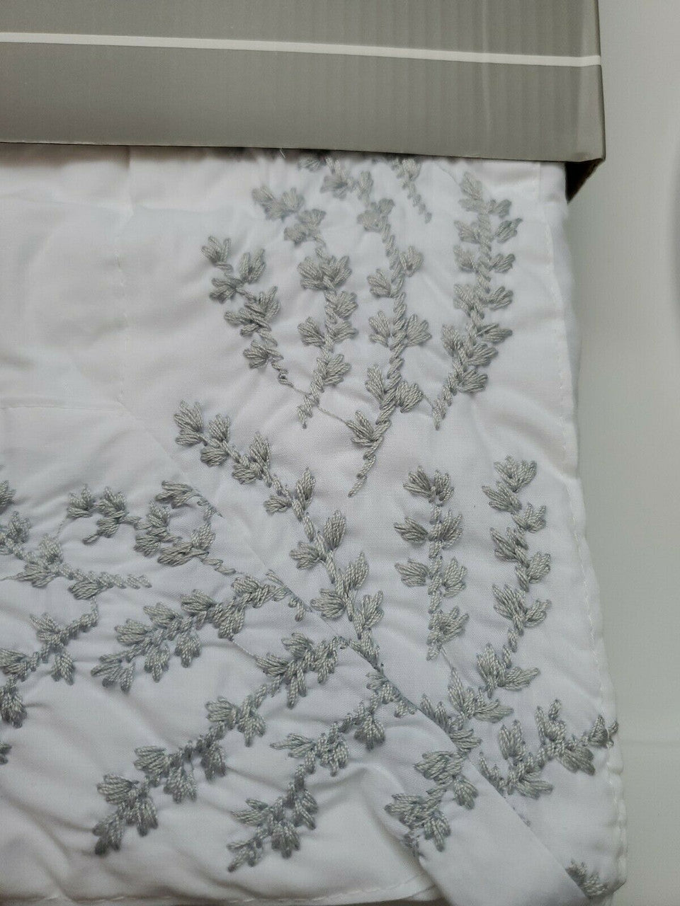 Folded white 100% cotton embroidered shower curtain from The Texture Collection shown in retail packaging